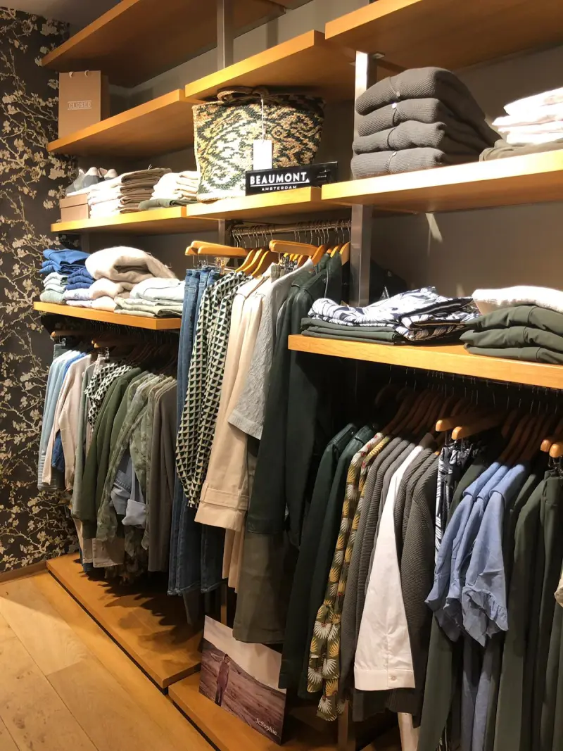 Wandrek in de winkel met gevouwen truien, een rieten mand en kleding in groen- en blauwtinten